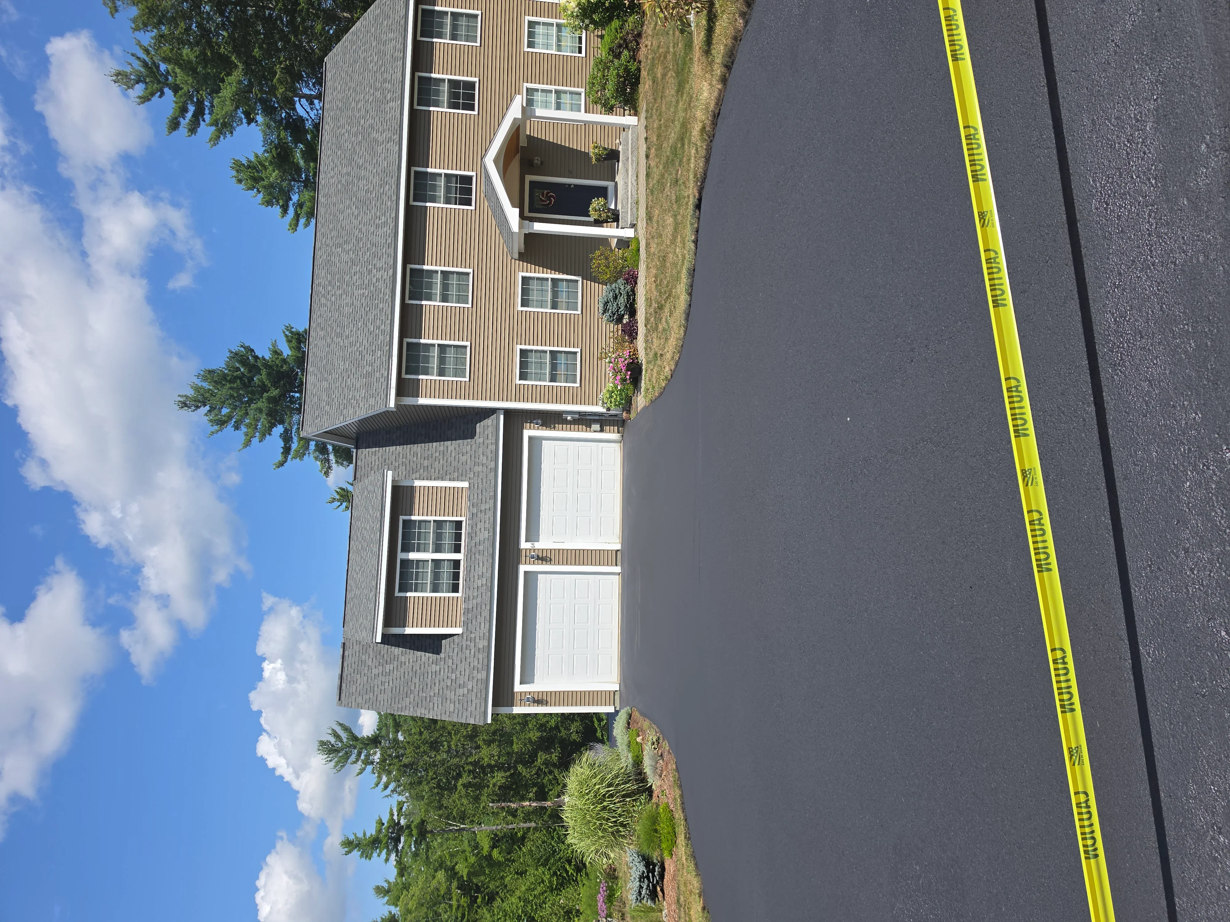 Freshly sealed asphalt driveway with dark protective coating in front of multi-unit residential building