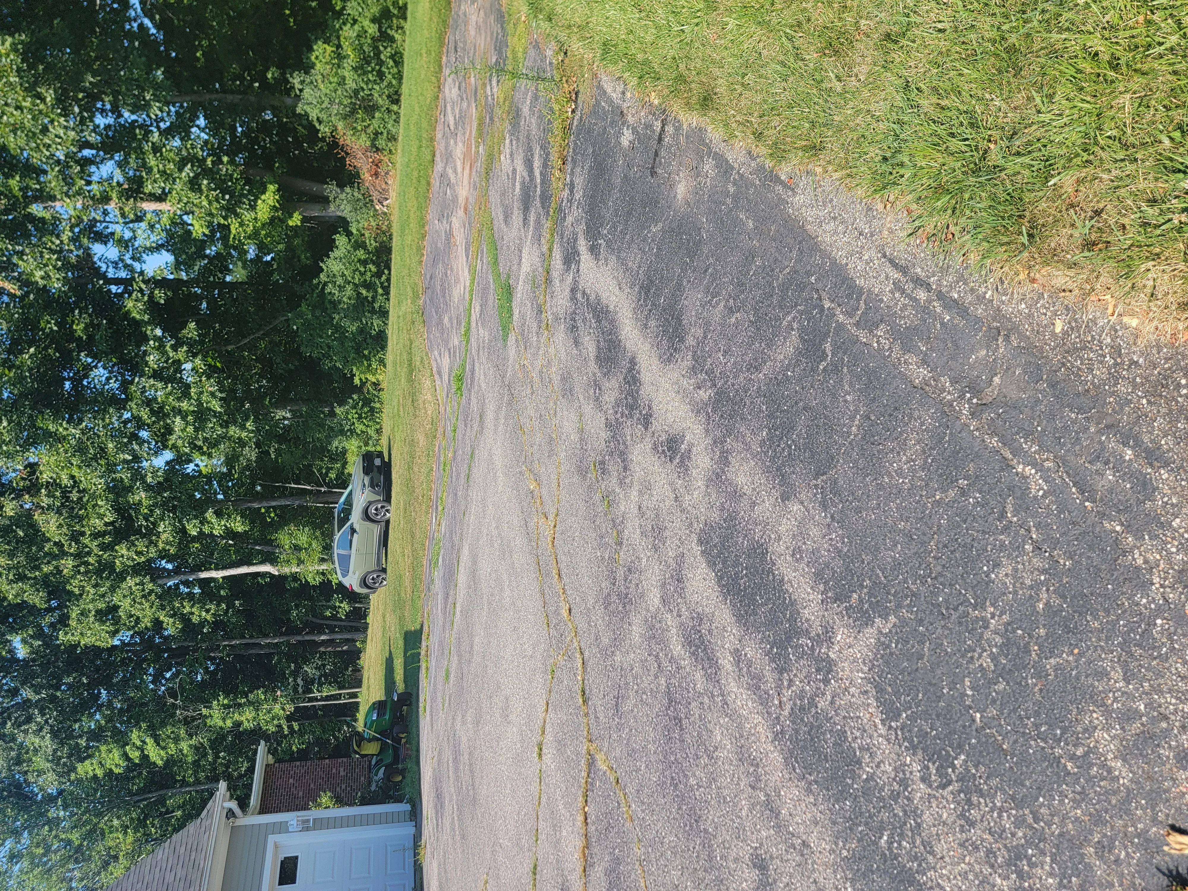 Sealed asphalt driveway with filled cracks and manicured grass edges